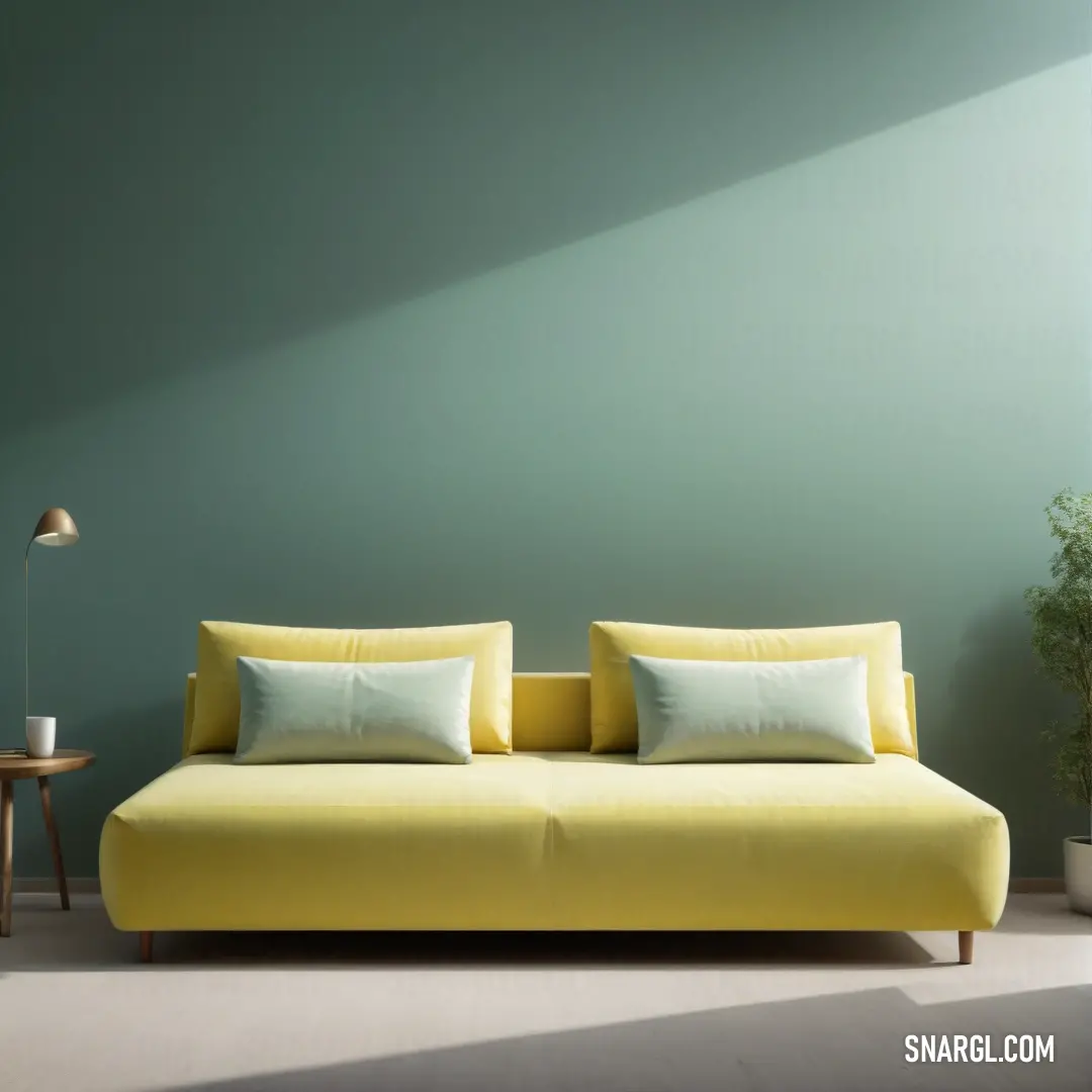 Yellow couch with pillows on it in a room with a green wall and a table with a lamp. Color Light khaki.
