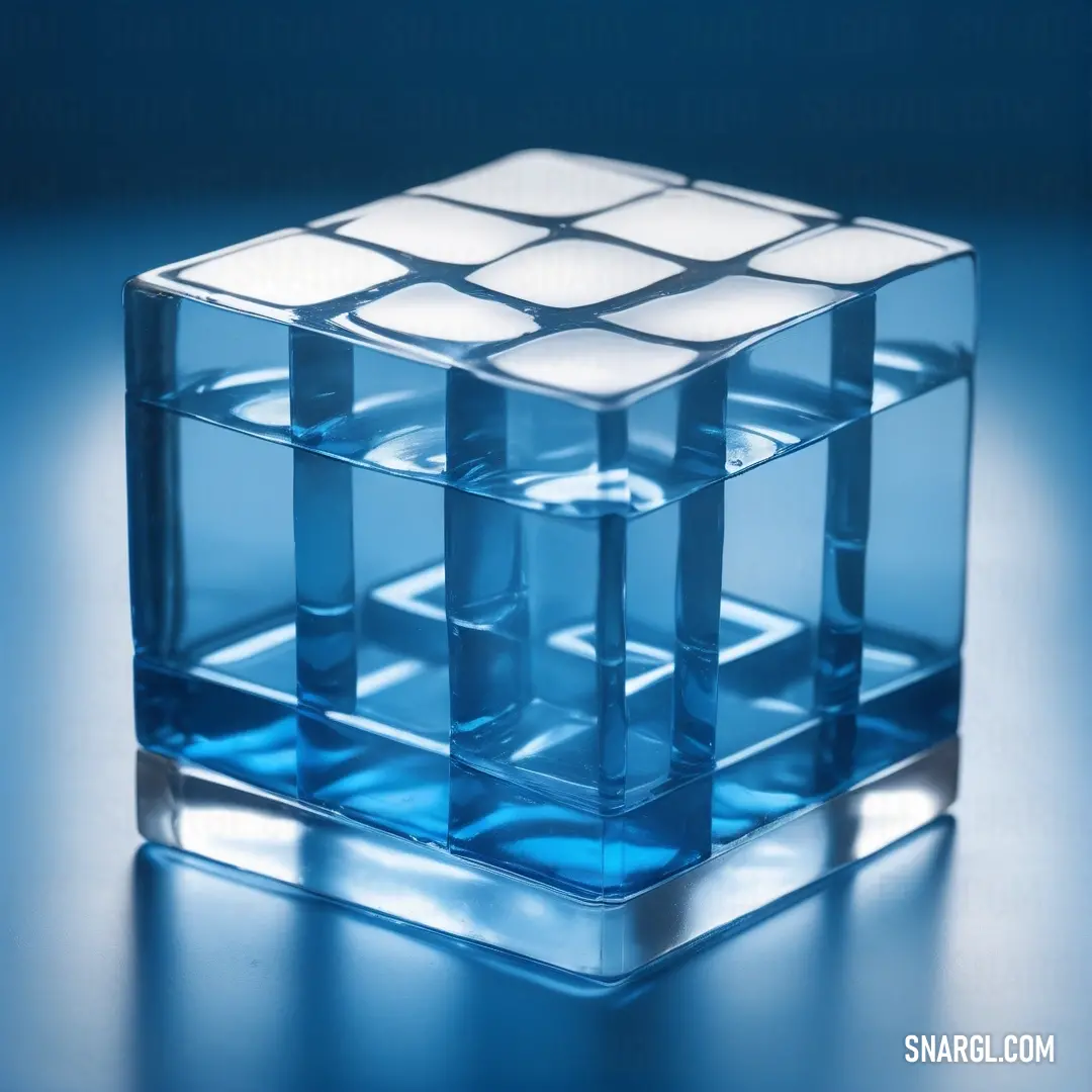 A crystal-clear cube of blue glass rests on a reflective blue surface, catching light as it casts subtle reflections. The interplay of light and color makes this image an elegant and captivating moment frozen in time.