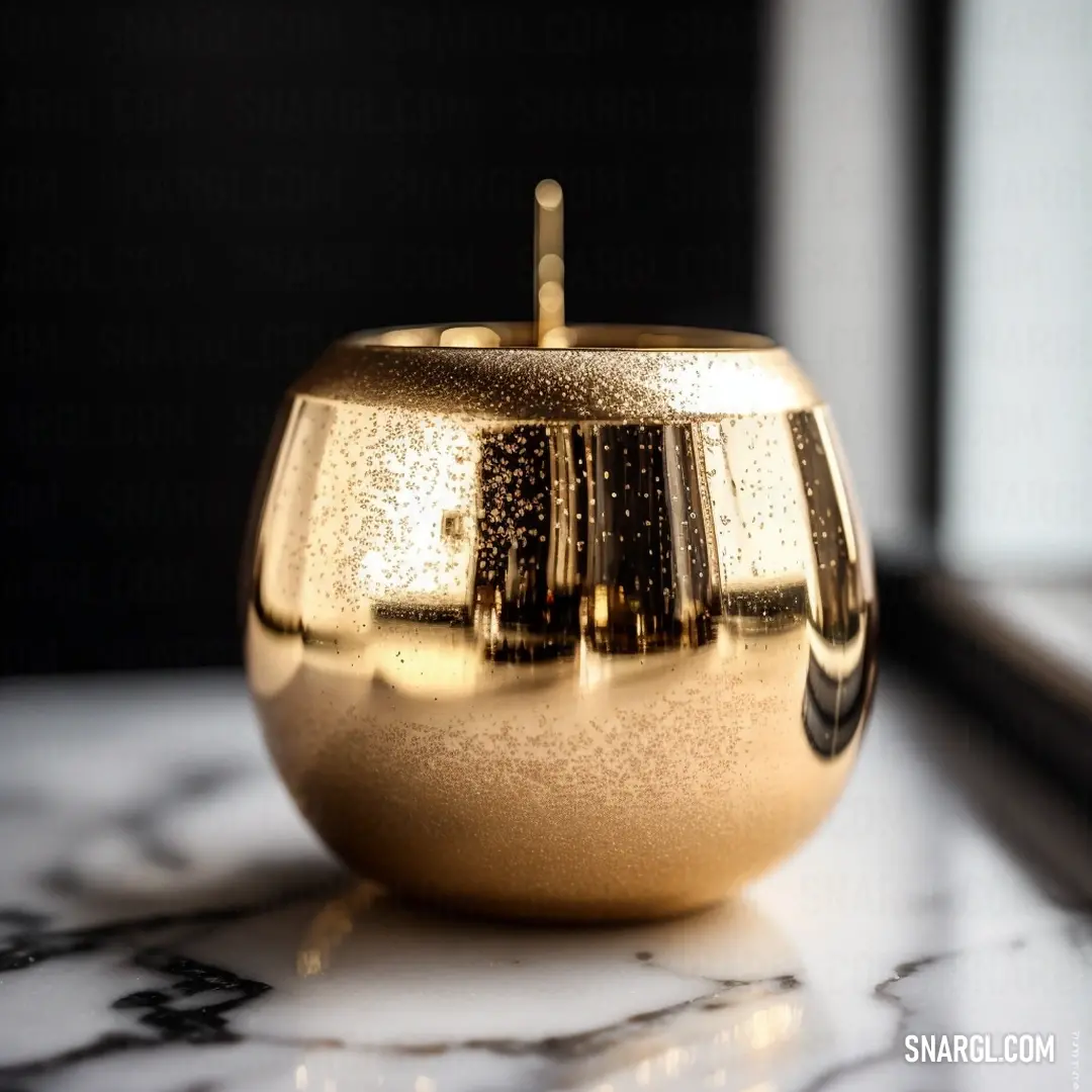 Golden apple on top of a marble counter top next to a window sill with a black curtain