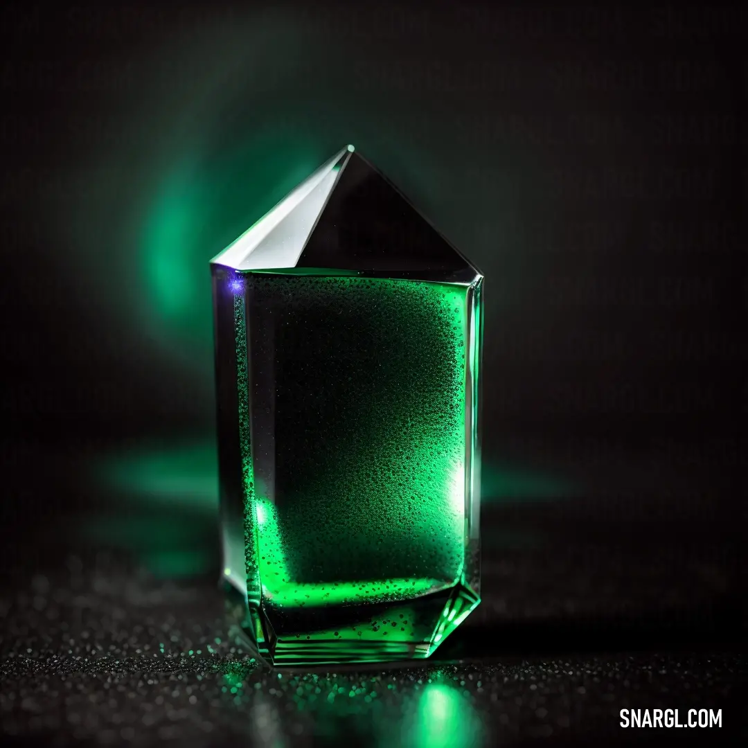 Green glass with a diamond on top of it on a table with a black background and a green light