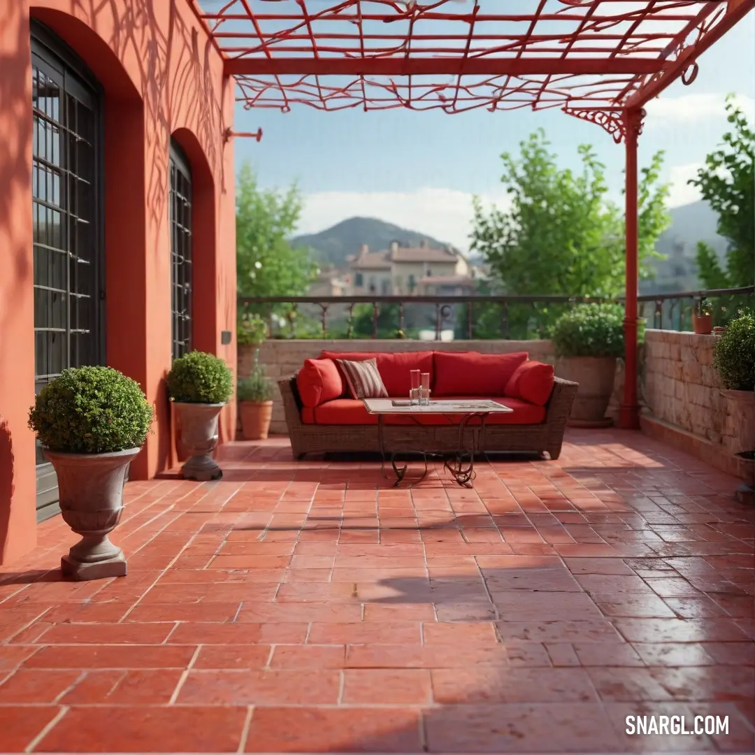 Red couch on top of a red tiled patio next to a potted planter and a window. Color CMYK 0,100,100,50.