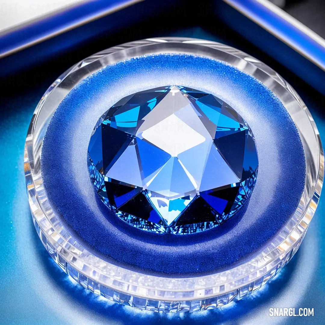 Blue diamond on top of a blue table top next to a mirror frame and a cell phone