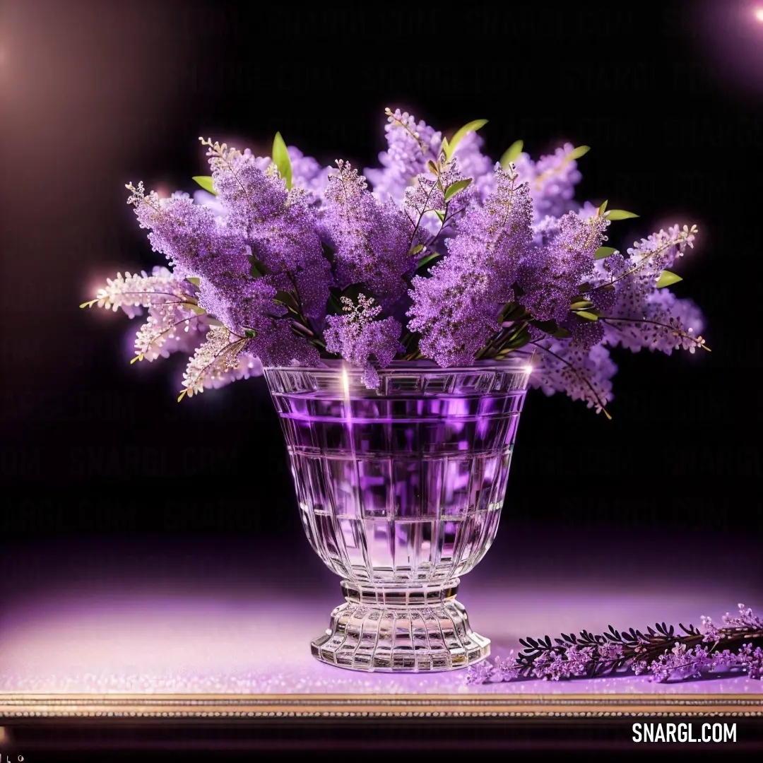 Glass vase filled with purple flowers on a table top next to a purple background