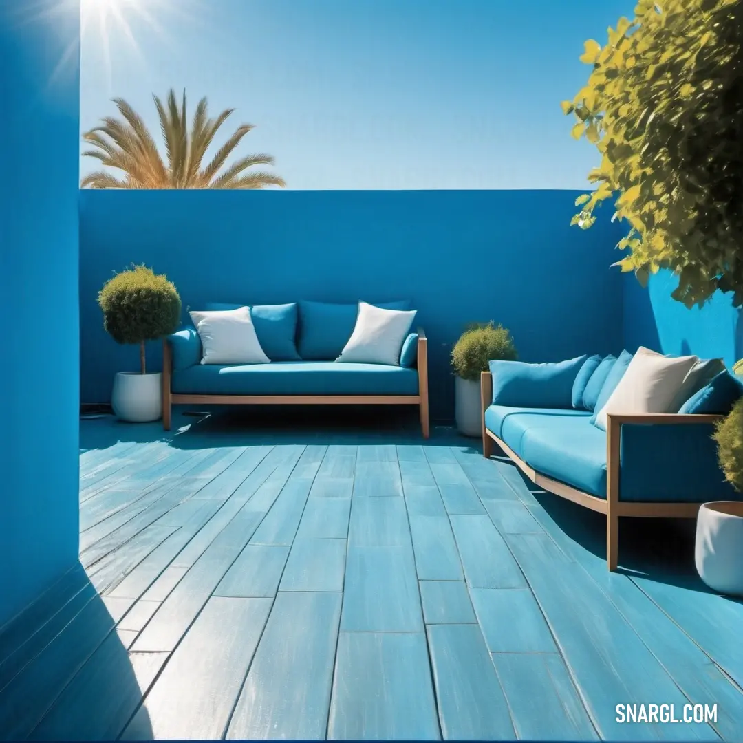 Blue couch and chair on a wooden deck with a blue wall and a tree in the background. Color RGB 0,103,165.