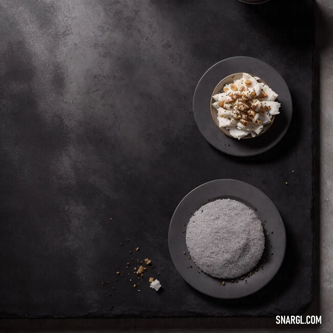 Two plates of delicious food rest on a black table, complemented by a steaming cup of coffee. The rich colors and textures of the food are highlighted against the dark background, creating an inviting, warm scene.