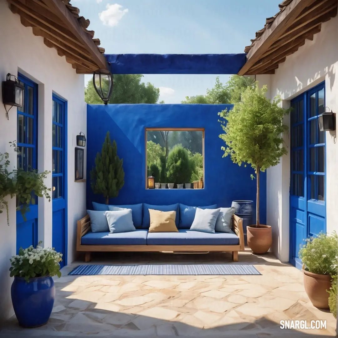 Blue couch under a mirror on a wall next to a blue door and windows. Example of #0054B4 color.