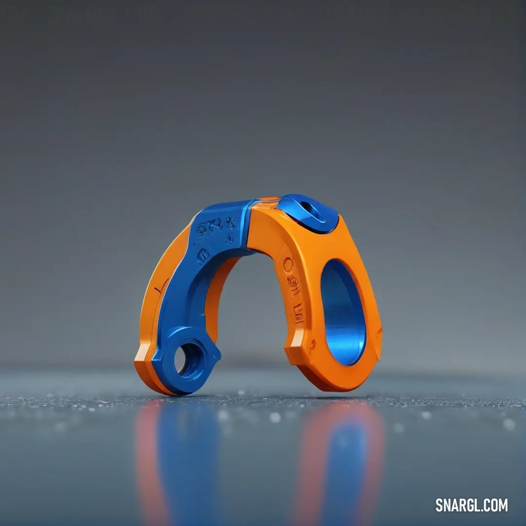 Pair of orange and blue scissors on a reflective surface with a reflection of the object in the background. Color RGB 0,84,180.