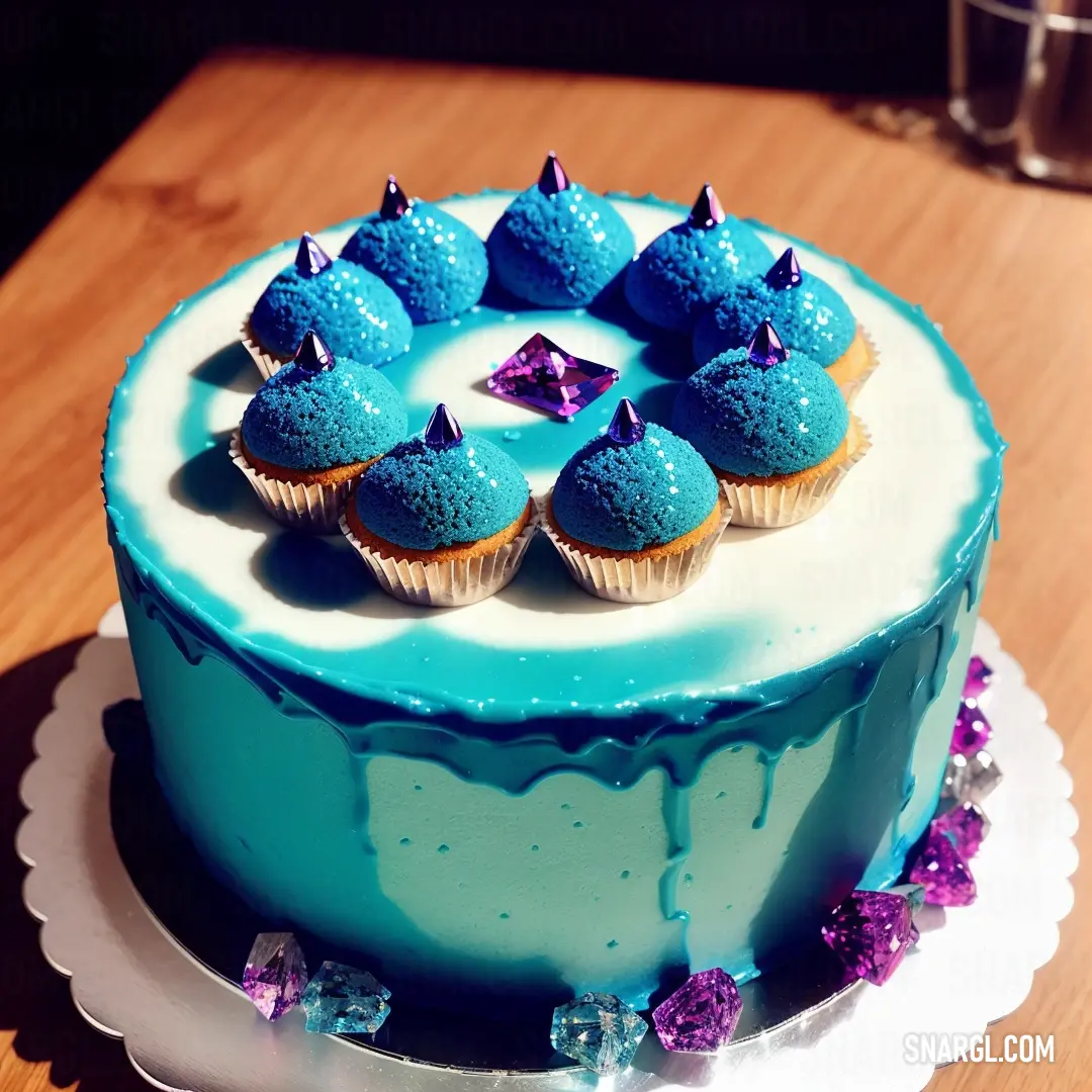 Blue cake with blue frosting and purple decorations on top of it on a table with a glass of water