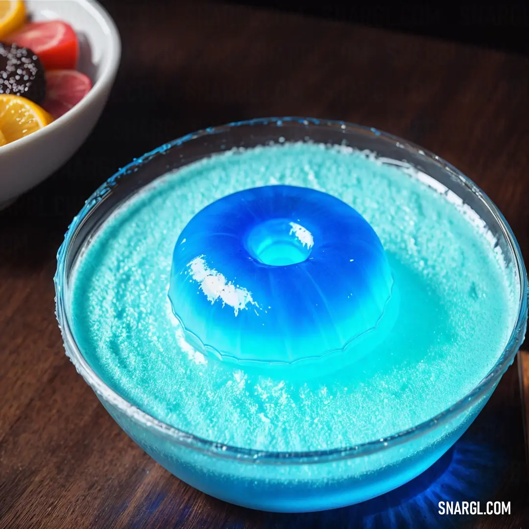 Bowl of blue liquid next to a bowl of fruit on a table with a knife and fork in it