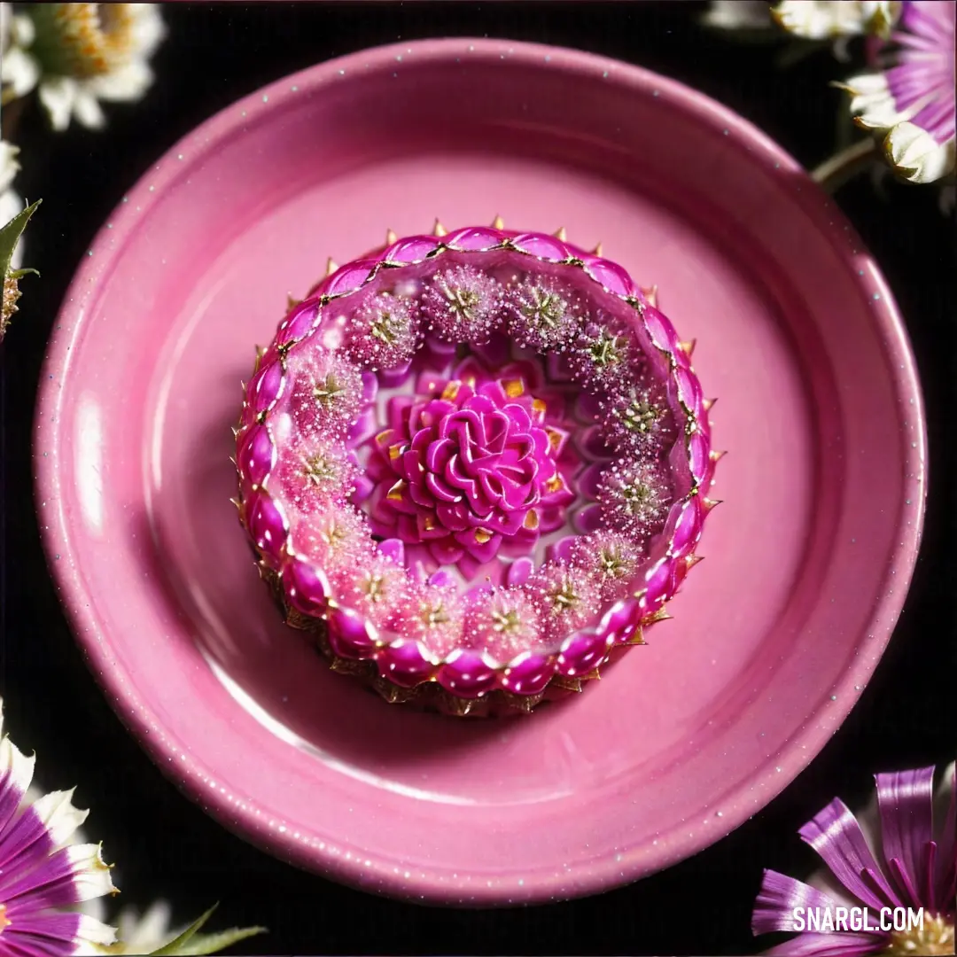 Pink plate with a flower in it on a table with flowers around it and a black background with a white border