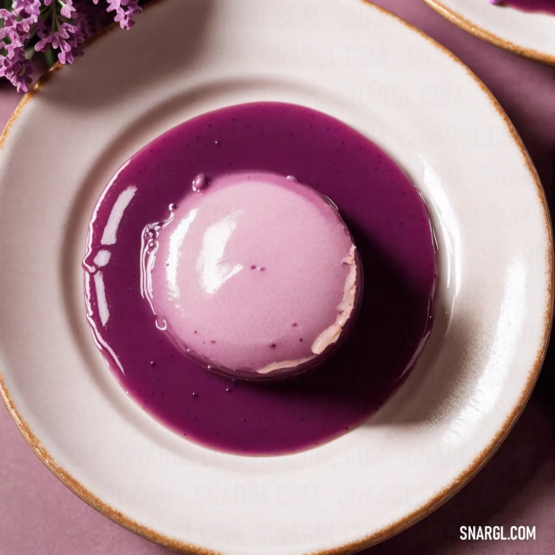 Purple substance in a white bowl on a purple table cloth next to a purple flower