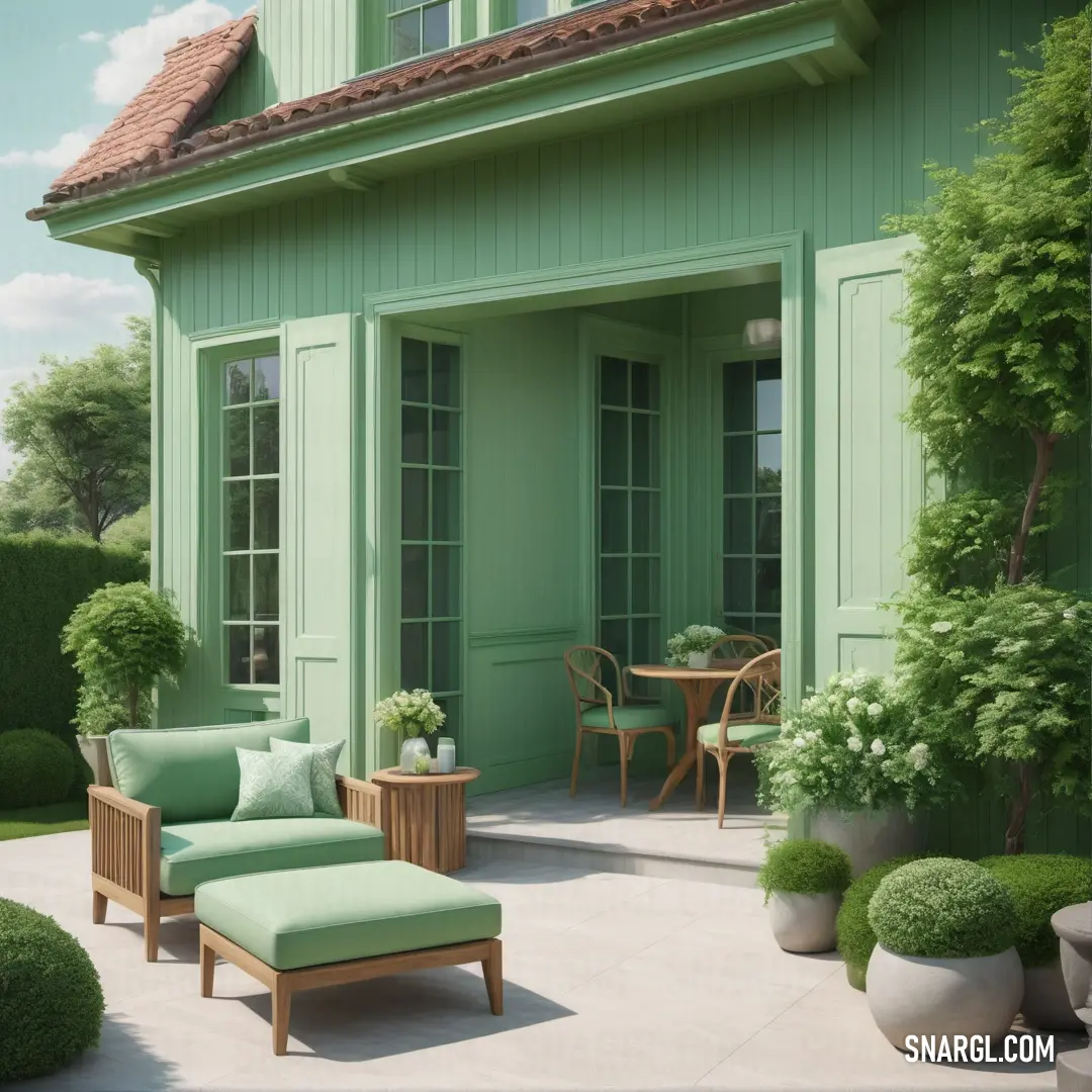Moss green color. Green house with a green chair and a green ottoman on a patio with potted plants and a table