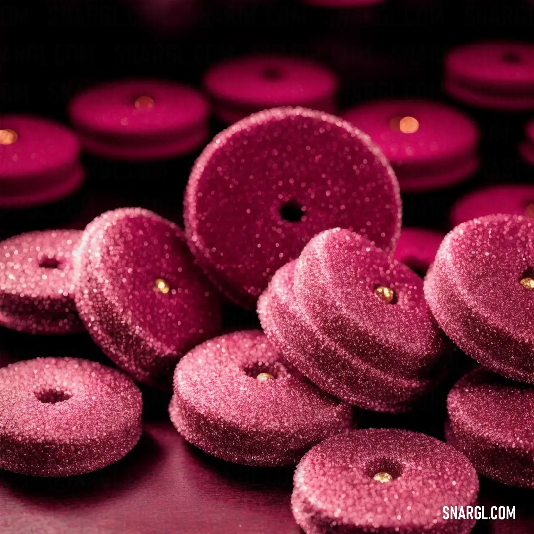 Pile of pink donuts on top of a table next to each other on a table top