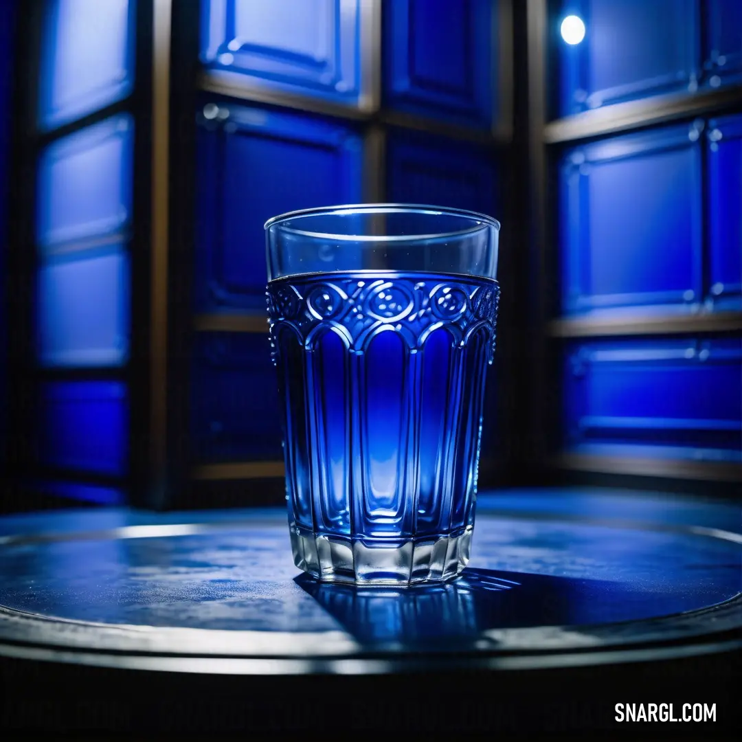 Glass of water on a table in front of a window with blue glass panels on the wall. Color RGB 0,0,128.