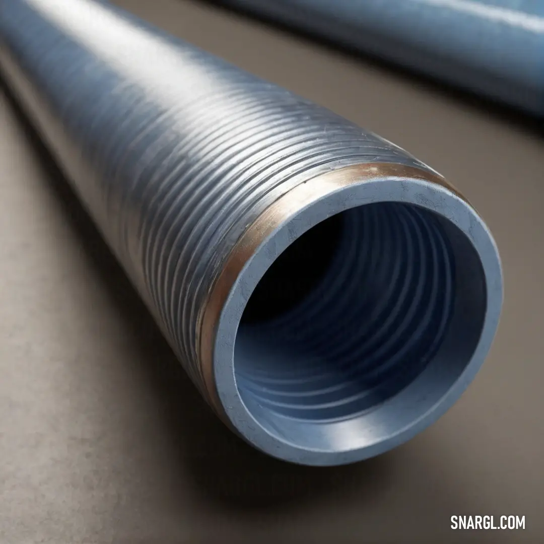 A dynamic close-up of a metal pipe resting on a table, highlighted by a striking blue tube positioned behind it. Together they exemplify the refined essence of NCS S 0502-R50B color in an intriguing arrangement.