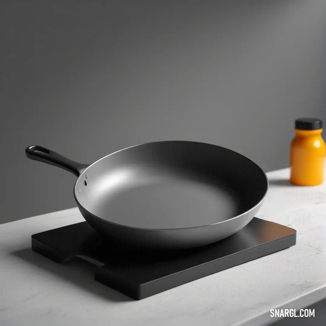 A frying pan elegantly placed on a kitchen countertop alongside a refreshing bottle of orange juice. The vibrant colors and warm lighting evoke a sense of homeliness and culinary inspiration.