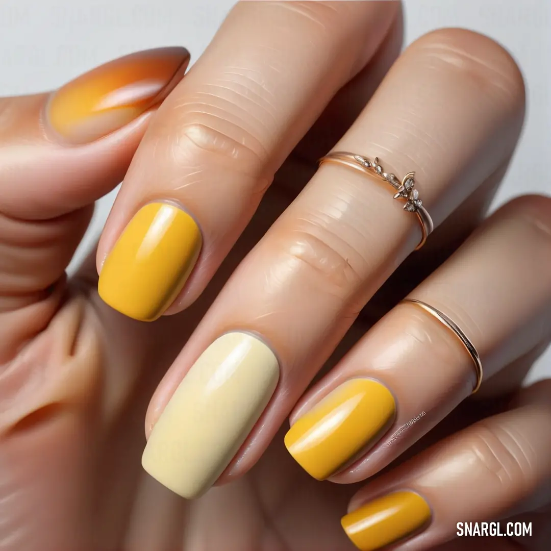 NCS S 0570-Y10R color. Manicure with yellow and white nail polishes on it's fingers and a ring on top of it