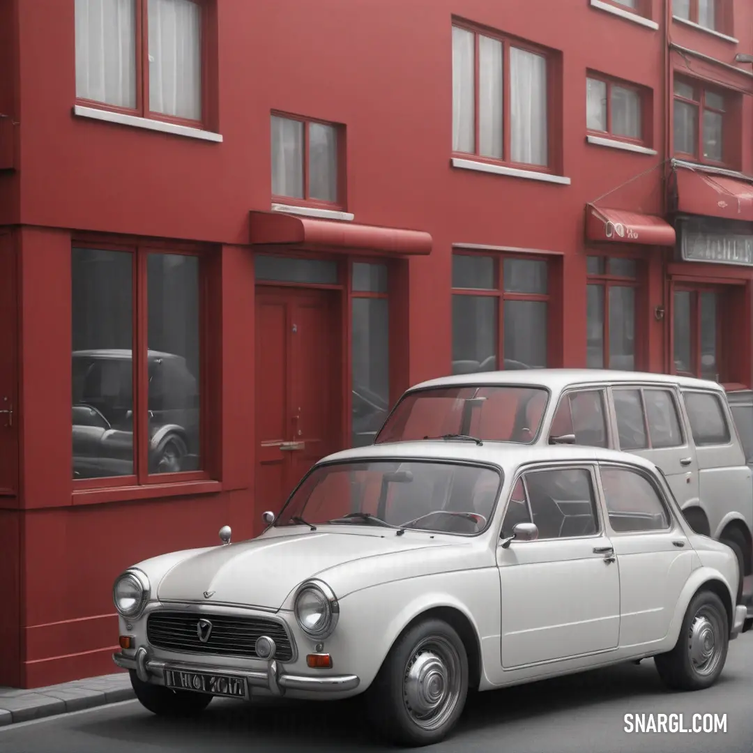 White car parked on the side of a road next to a red building with windows. Color CMYK 5,3,0,5.