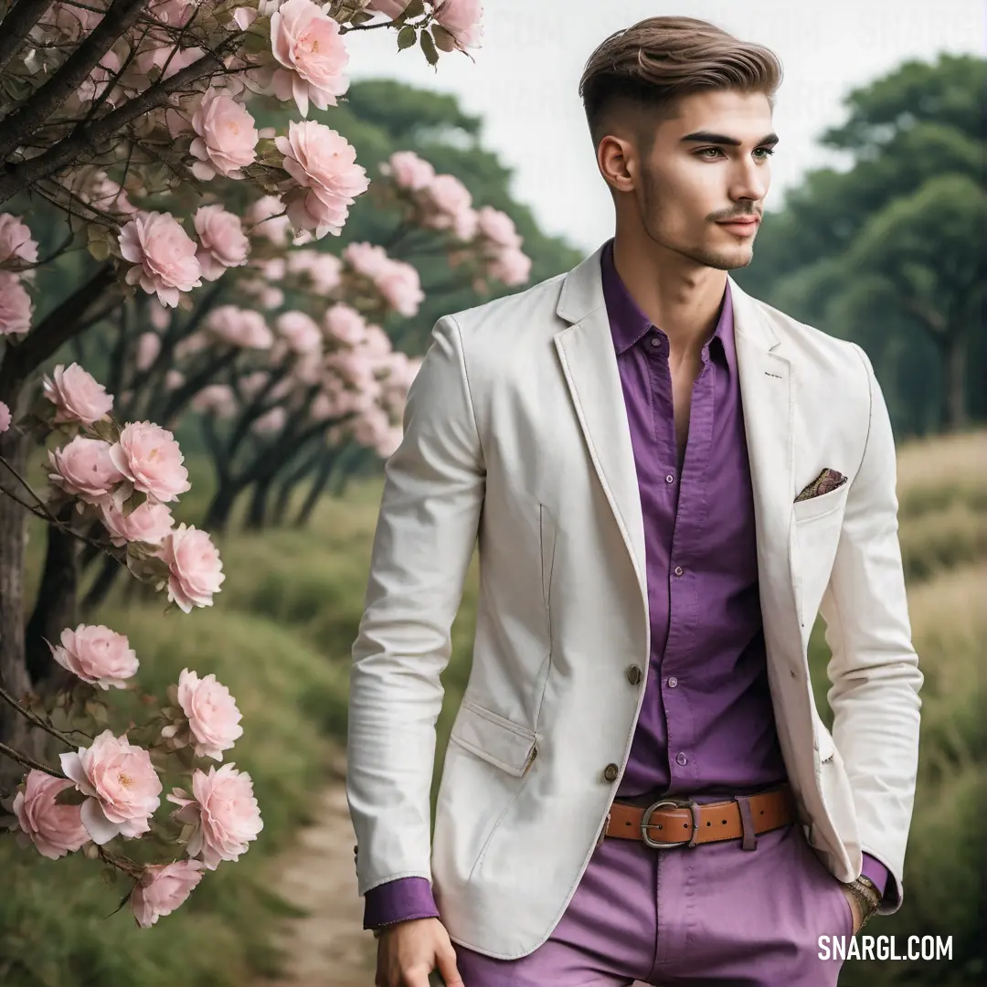 Man in a suit and purple shirt standing in front of a tree with pink flowers on it and a path. Example of RGB 225,231,233 color.