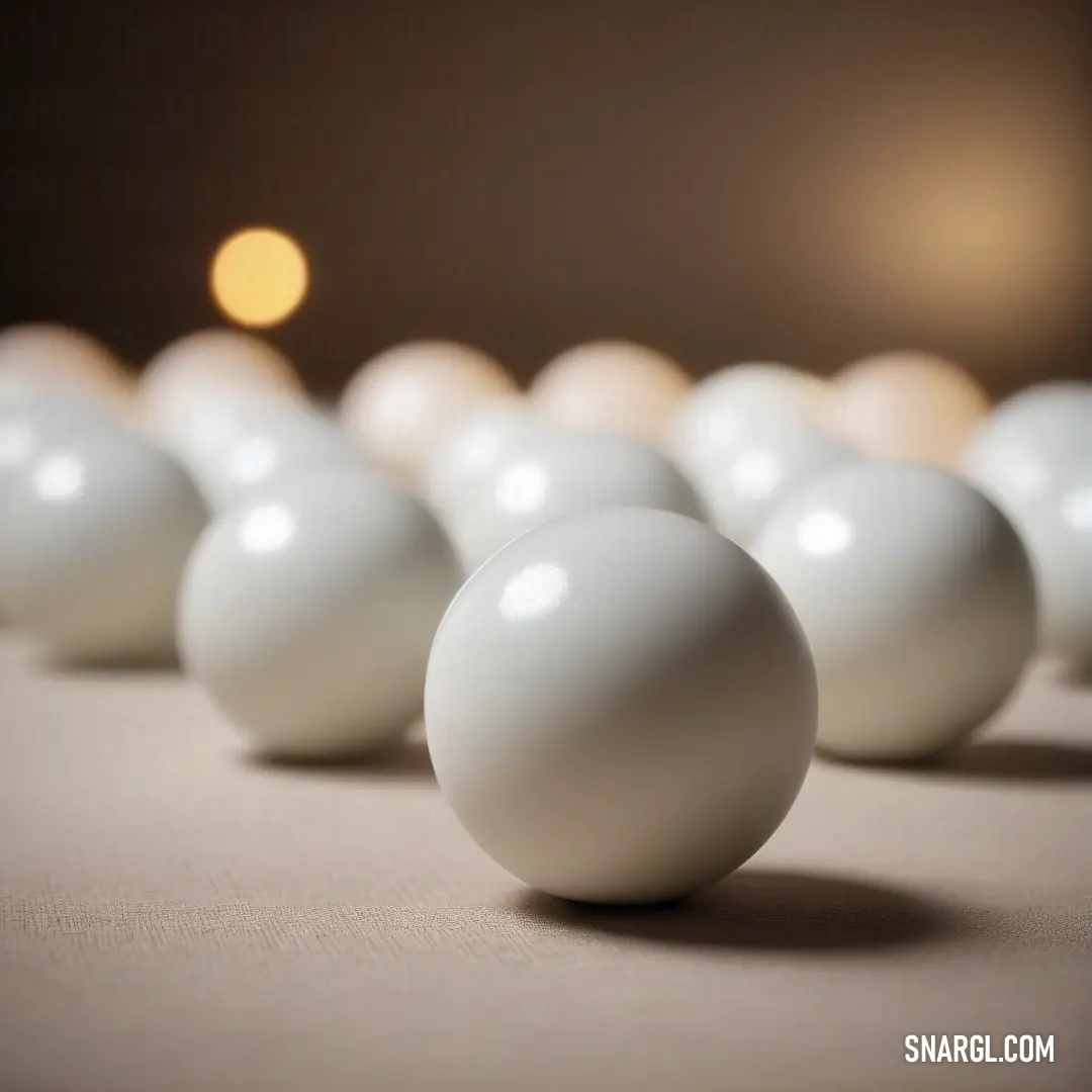 A row of pristine white balls sits in perfect alignment on a table, resting against a soft tablecloth. The simplicity of the scene, paired with the crisp white colors, creates a clean, minimalist aesthetic.