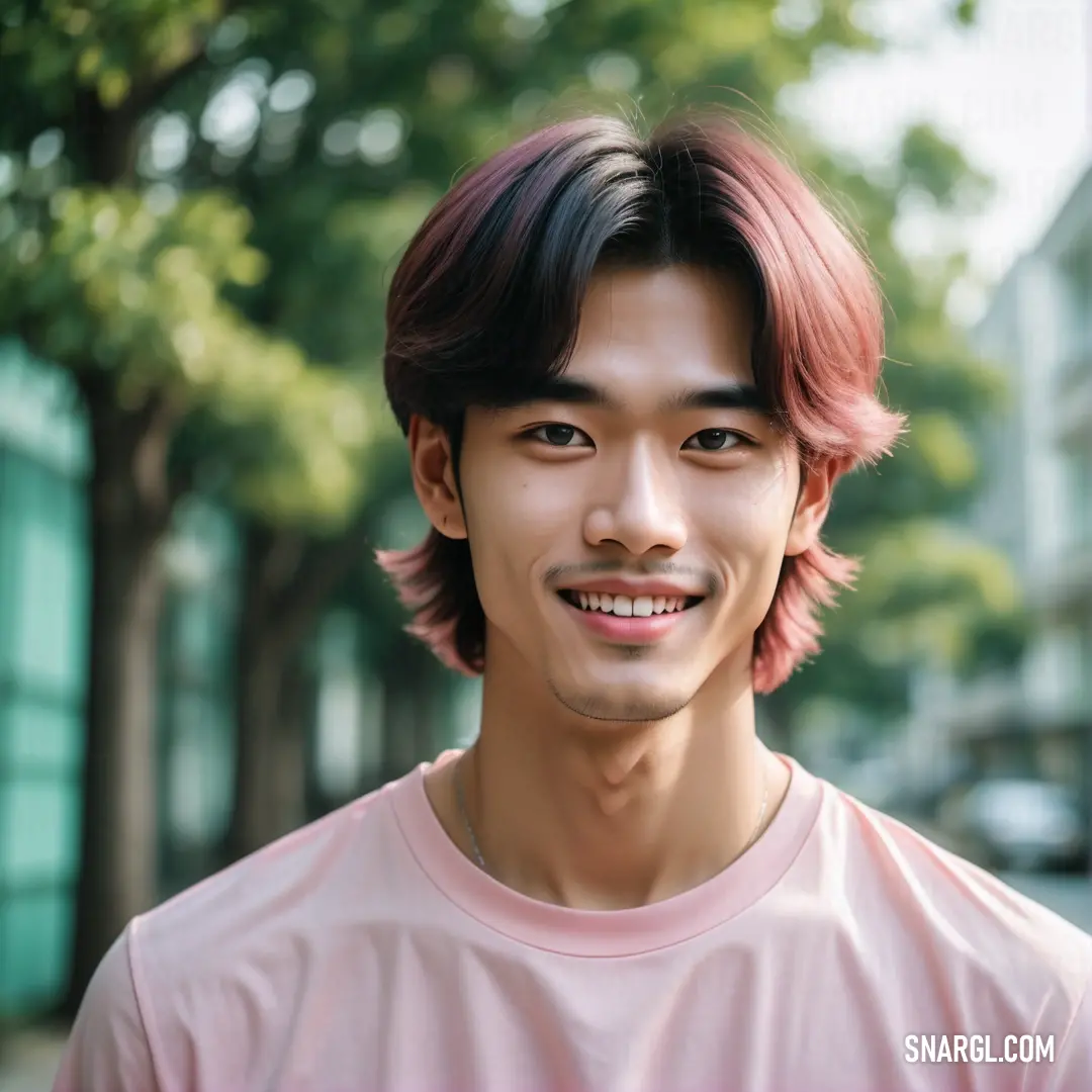 Man with a pink shirt and a pink shirt on smiling at the camera with trees in the background. Color #F4D3D3.