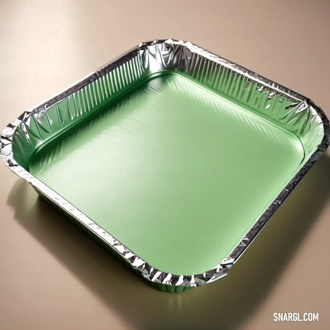 Green tin foil tray on a brown table top with a shadow of a person's hand on the bottom. Example of RGB 201,238,159 color.