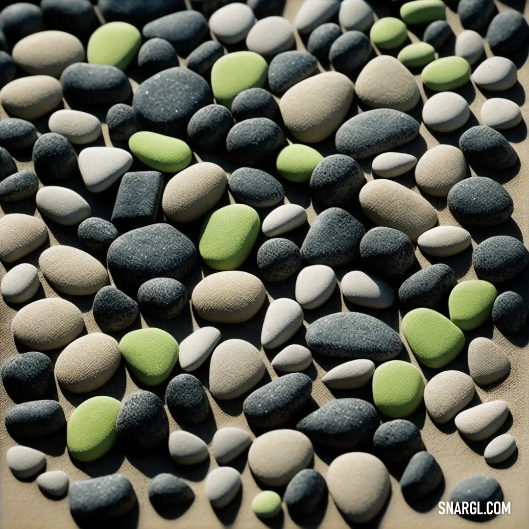 Bunch of rocks on a table together with a green one on top of them and a black one on the bottom. Color NCS S 1040-G30Y.