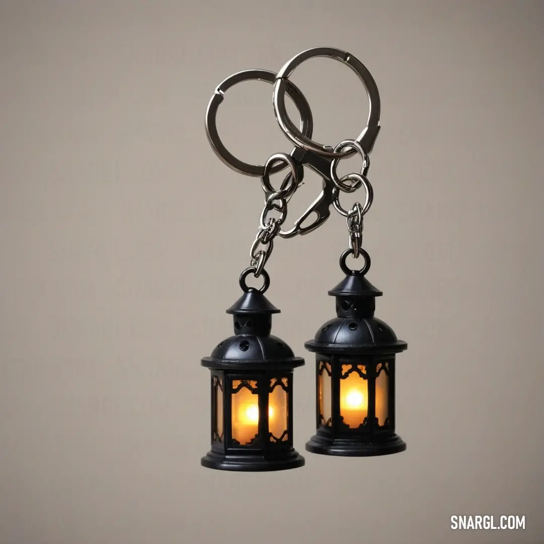 An elegant display of two black lanterns illuminated from within, gracefully suspended from a metal hook. Their striking contrast against a soft gray background highlights their intricate design, creating a charming and nostalgic atmosphere.