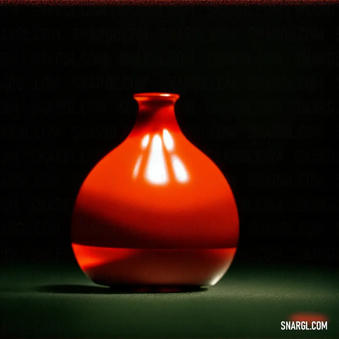 Red vase on a green surface in the dark room with a black background. Color #E23403.