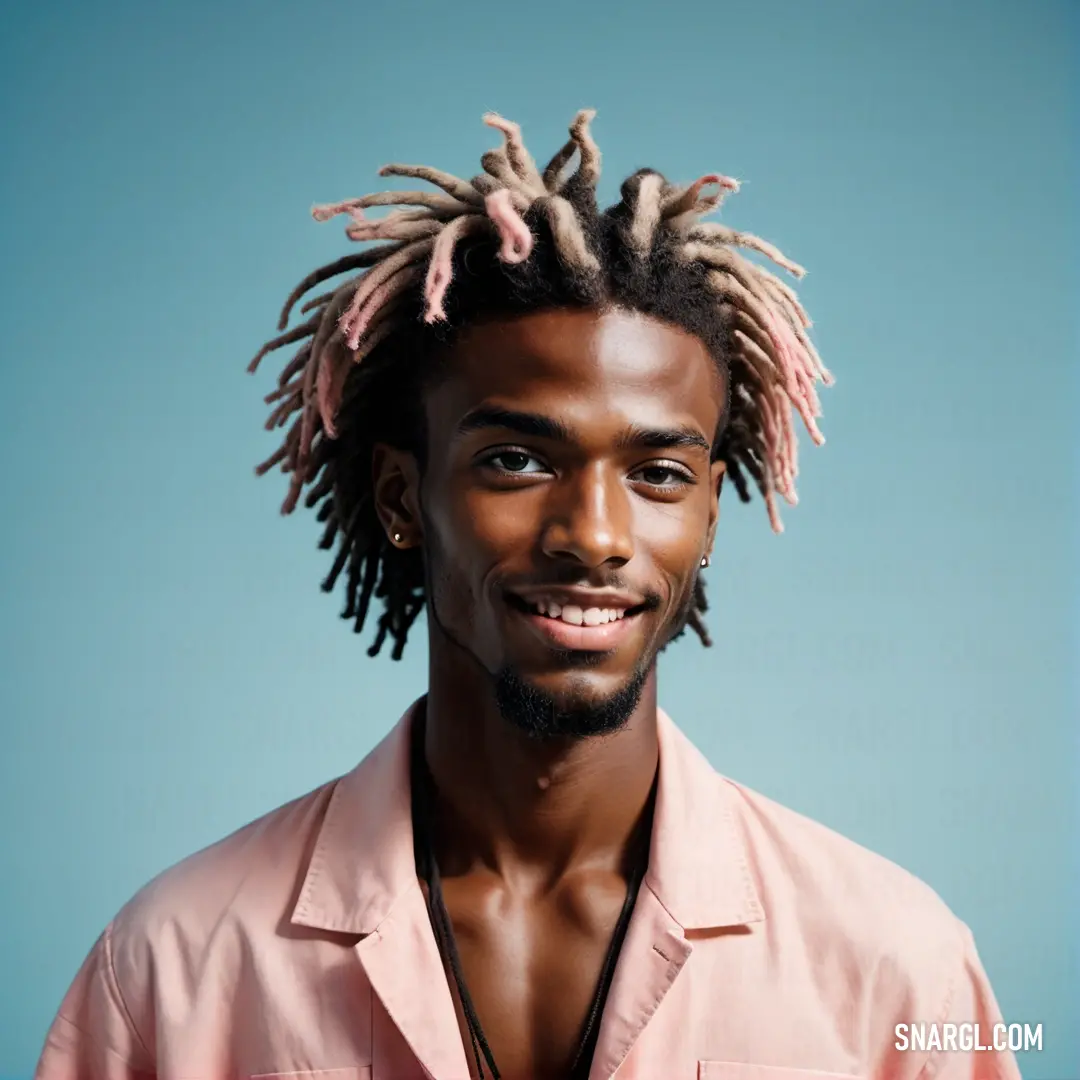 Man with dreadlocks on his head and a pink shirt on his shirt is smiling at the camera. Example of RGB 228,189,179 color.