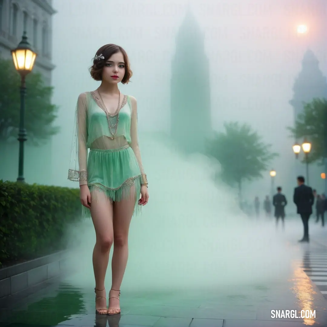 Woman in a green bodysuit standing on a sidewalk in the fog. Color CMYK 35,0,22,0.