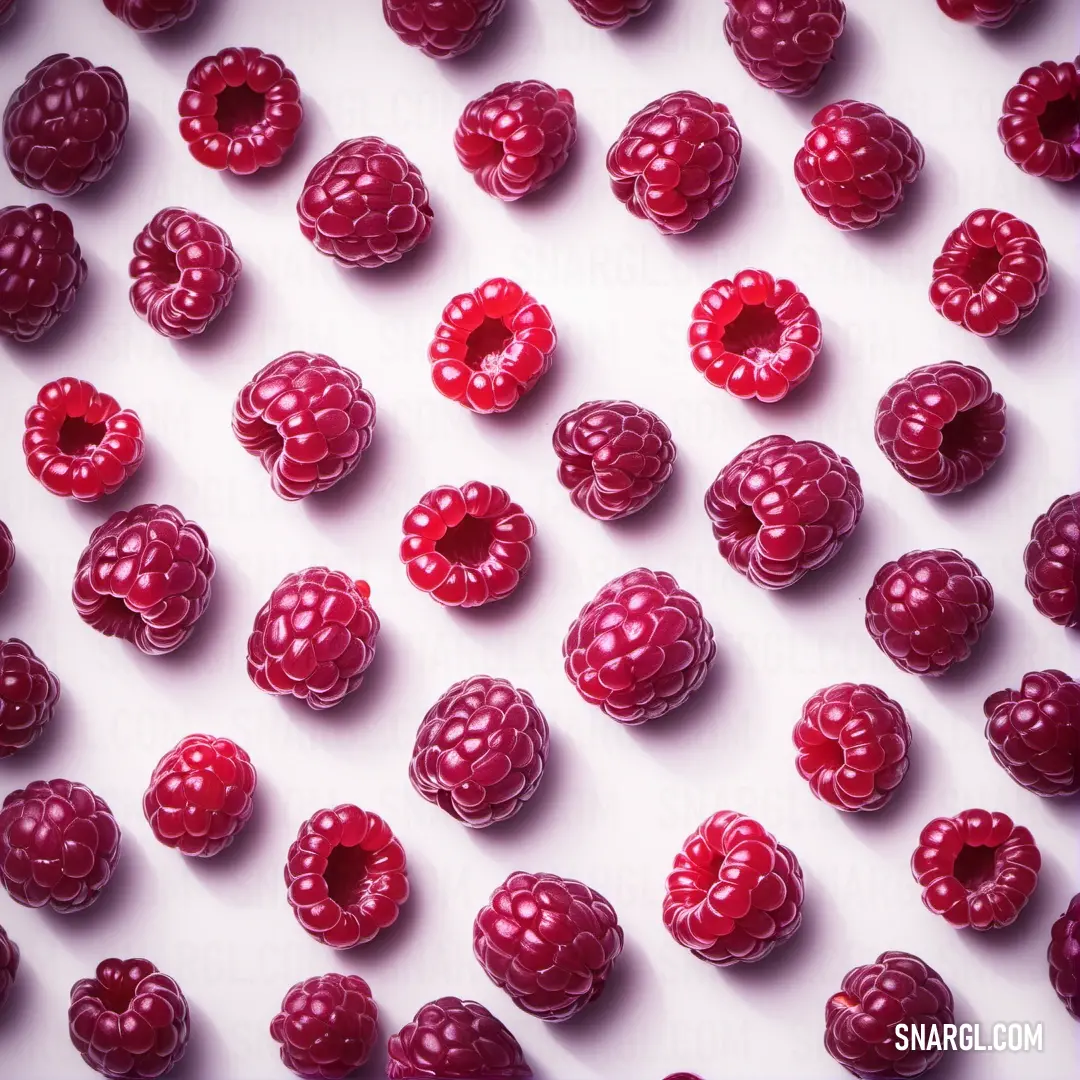 Bunch of raspberries are arranged on a white surface with a pink background. Example of CMYK 0,100,45,25 color.