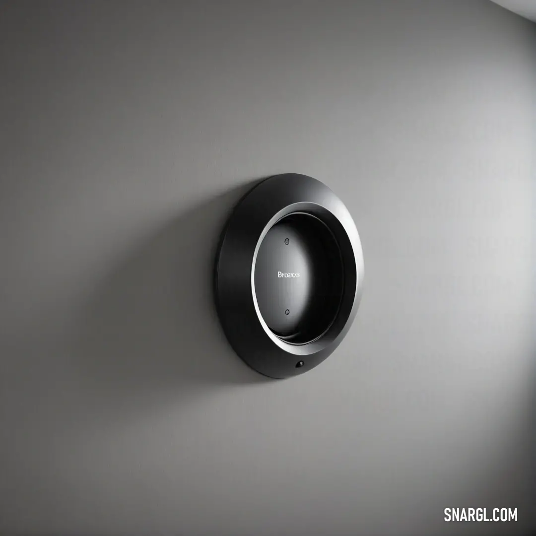 An elegant black and silver clock hangs on a gray wall, combining functionality with aesthetic appeal. Its minimalist design complements the simplicity of its surroundings while making a timeless statement of style.