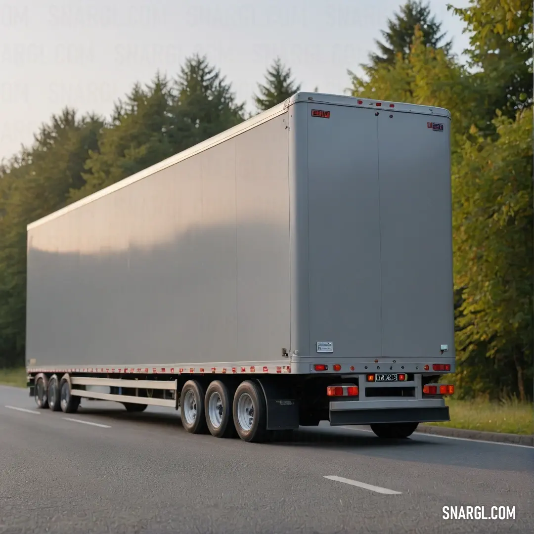 A sleek semi truck gracefully navigates a winding road surrounded by a lush forest, showcasing the vibrant colors of nature and the industrial beauty of modern transportation. This scene highlights the harmony between machinery and the great outdoors.