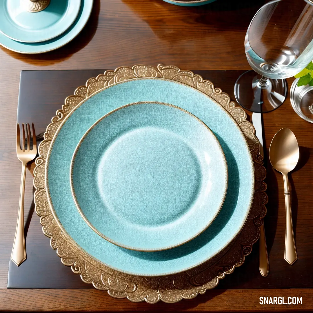 Table set with a blue plate and silverware and a glass of water and a gold rimmed fork and knife. Color RGB 221,178,126.