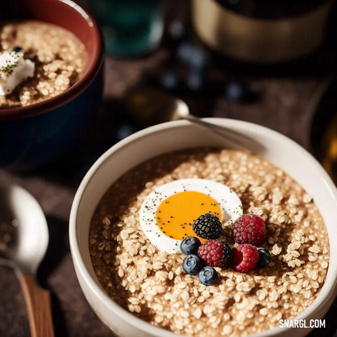 Bowl of oatmeal with berries and an egg on top of it with a spoon and a cup of wine. Color #DAA47D.