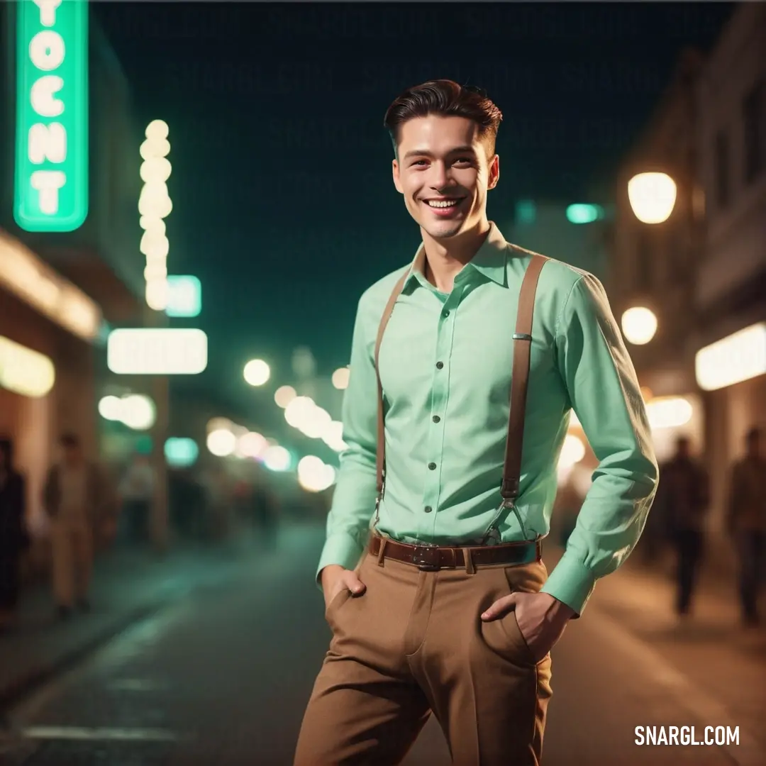 Man in a green shirt and brown pants standing on a street at night with his hands in his pockets. Color #85DDBA.