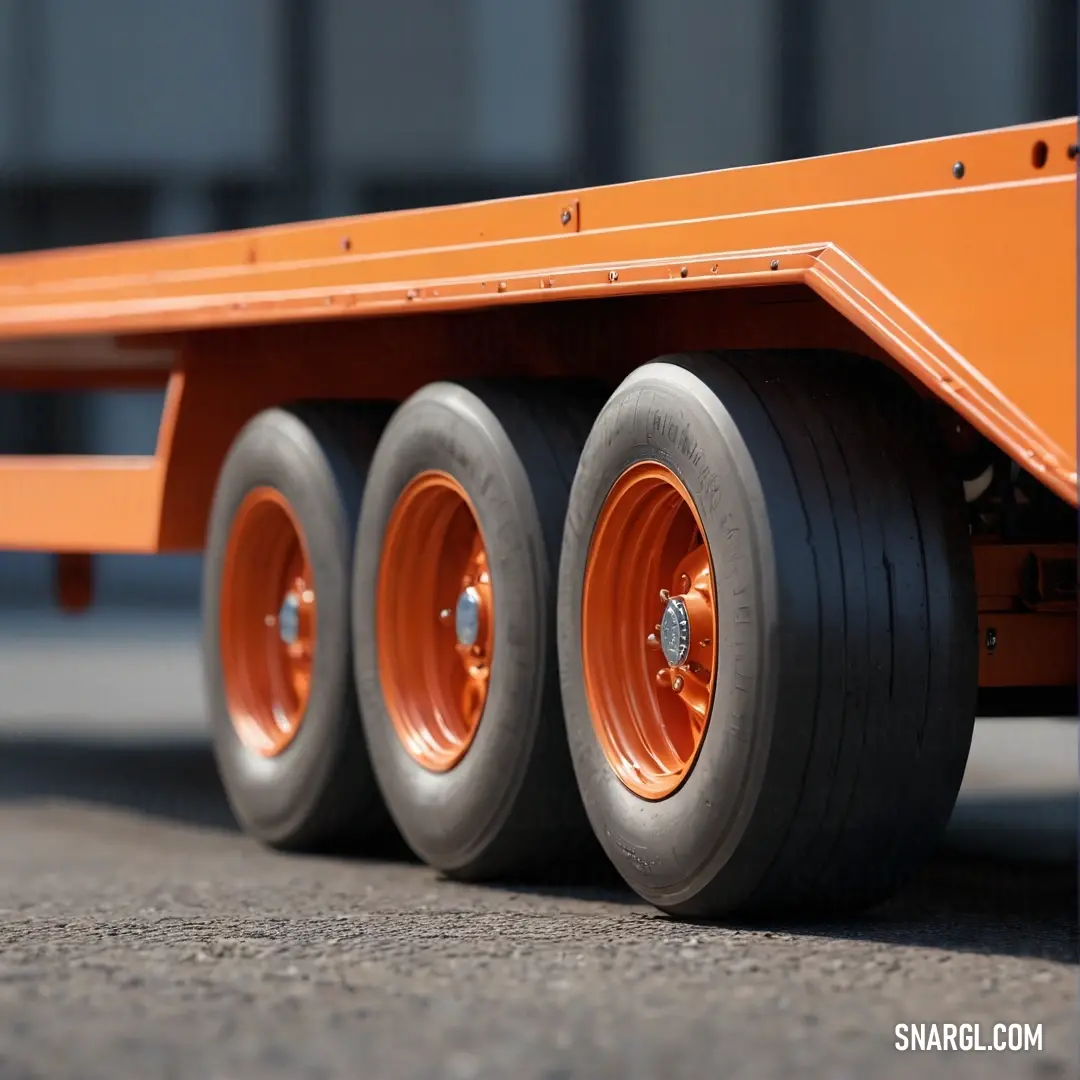 A striking image of a flatbed trailer featuring vibrant orange wheels, sitting beside a building. The rugged charm of the trailer contrasts beautifully with the clean lines of the structure, highlighting a blend of utility and aesthetic appeal in the land