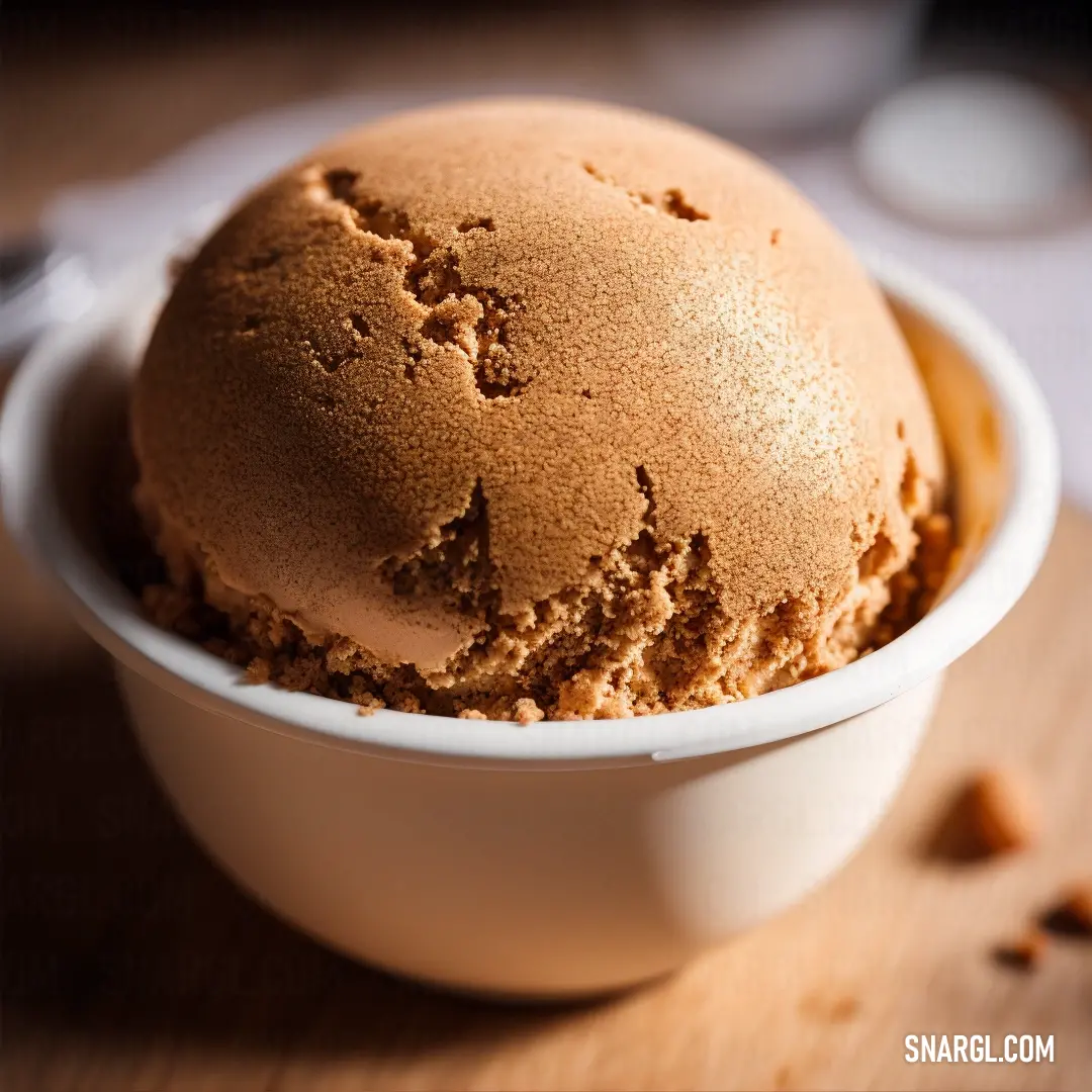 Bowl of ice cream on a wooden table with a spoon and spoon rest on the table next to it. Color RGB 225,135,60.