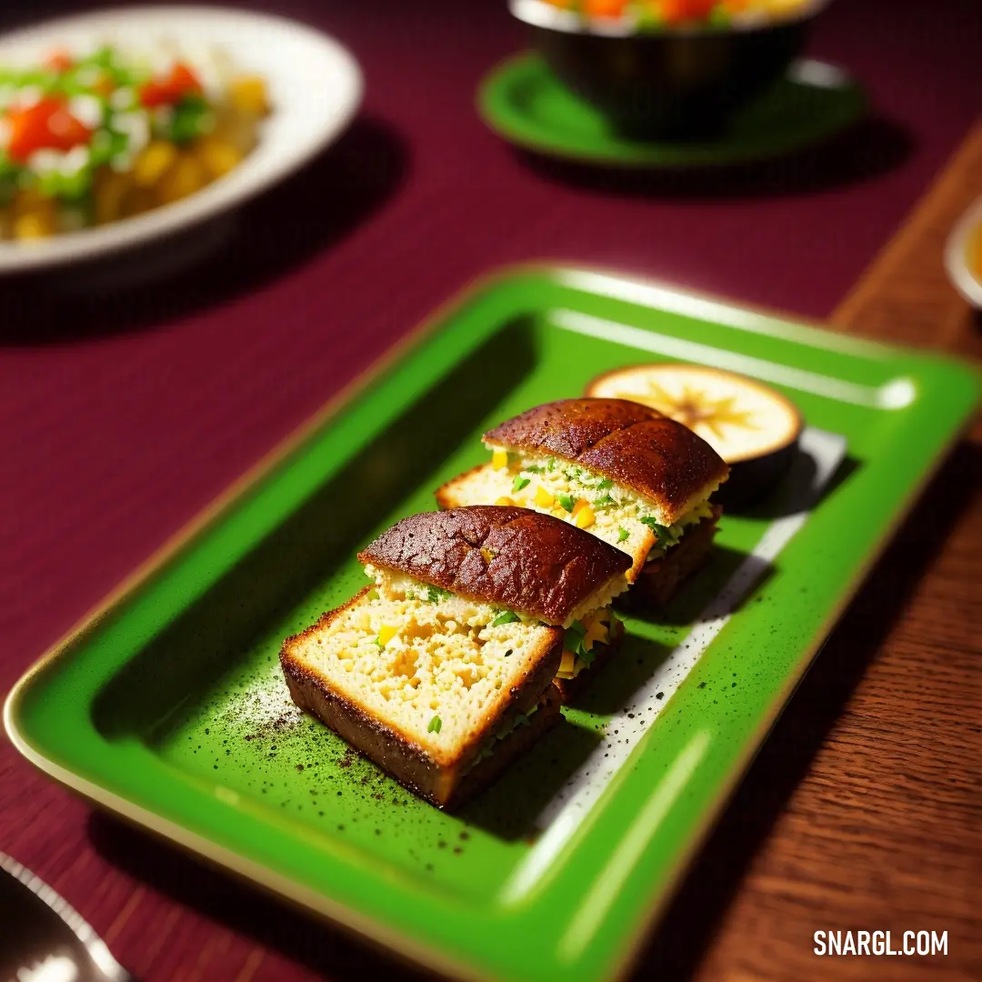 Green plate topped with a sandwich and a salad on a table next to a bowl of salad and a fork. Color CMYK 68,0,100,7.