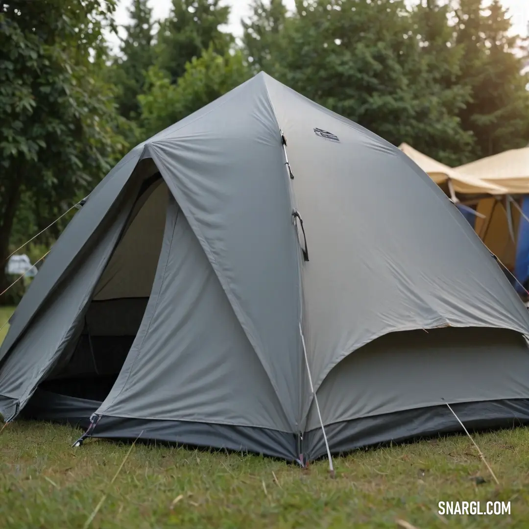 A well-structured tent set up on lush grass, surrounded by towering trees that provide a natural backdrop, creating a serene retreat in the great outdoors. The vibrant colors of nature complement the scene.