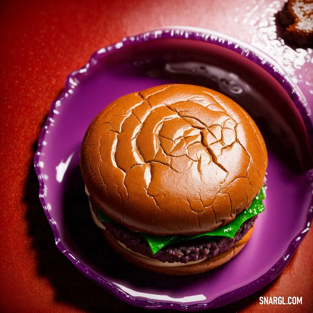 Purple plate with a hamburger on it on a red table top with a cup of coffee and a cookie. Color NCS S 3560-Y20R.