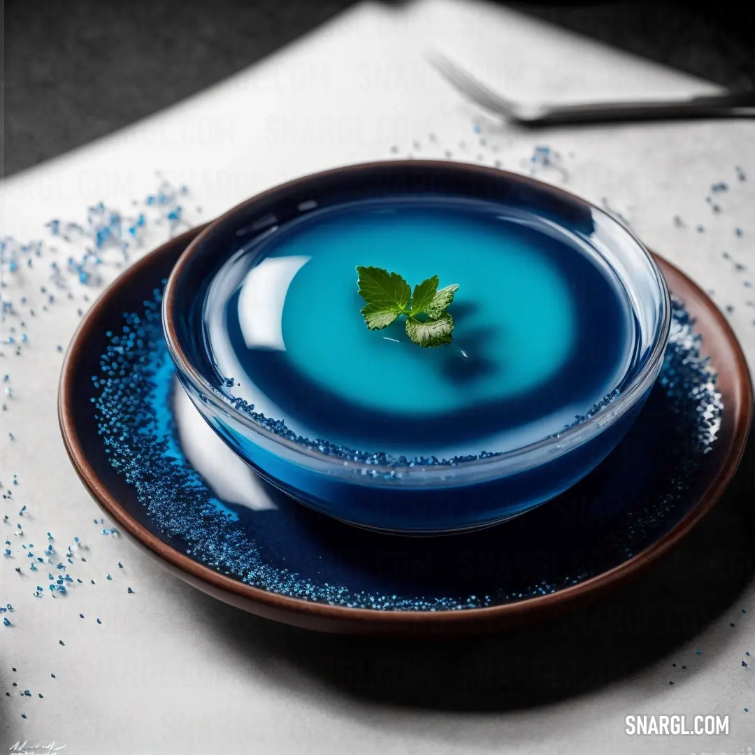 A blue plate topped with a fresh green leaf, paired with a fork and knife set neatly beside it, creates an elegant and minimalistic dining setting. The color of the plate is vivid, emphasizing the simplicity and beauty of the meal's presentation.