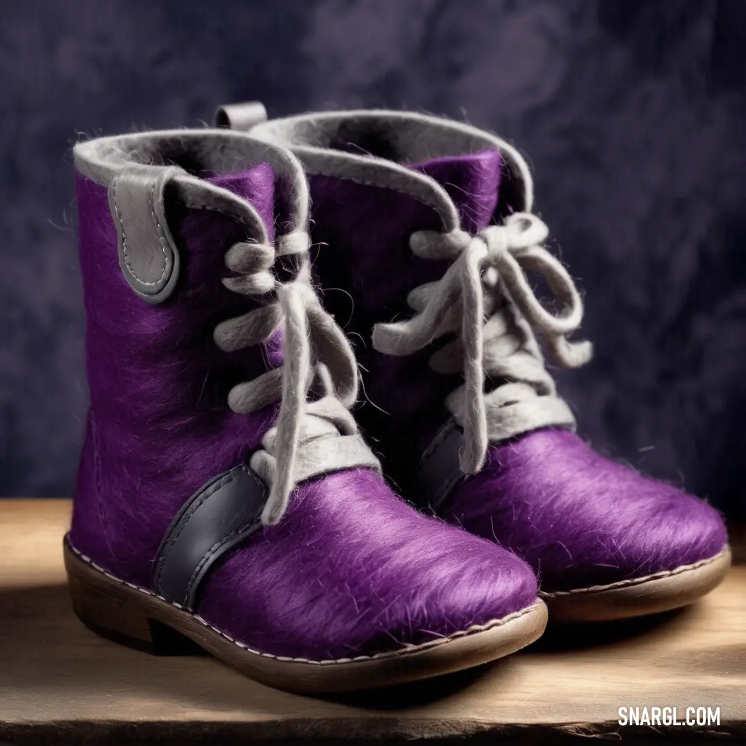 Pair of purple boots with white laces on them on a wooden table with a blue background. Example of #6D0168 color.