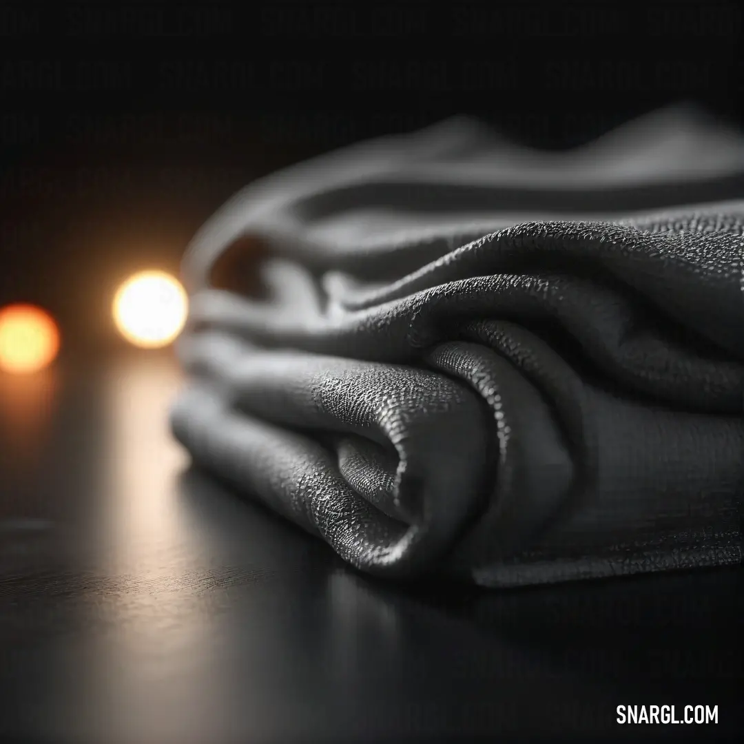 An evocative black-and-white photograph featuring a delicate cloth draped over a table, illuminated by soft light in the background. This serene scene captures a moment of stillness and beauty, highlighting the interplay of light and texture.