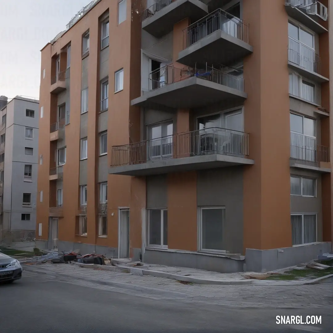 A stunning tall orange building featuring elegant balconies that enhance its architectural charm. The second-floor balconies offer a great view of the surroundings. This vibrant structure stands out with its unique color, which exemplifies a blend of urba