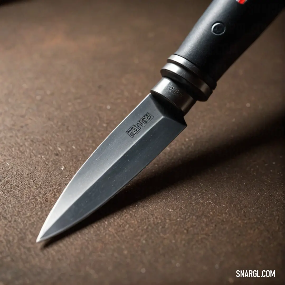 A classic knife elegantly laid out on a table, showcasing its black handle and striking red stripe on the blade. The image captures the beauty and precision of craftsmanship involved in creating exceptional kitchen tools.