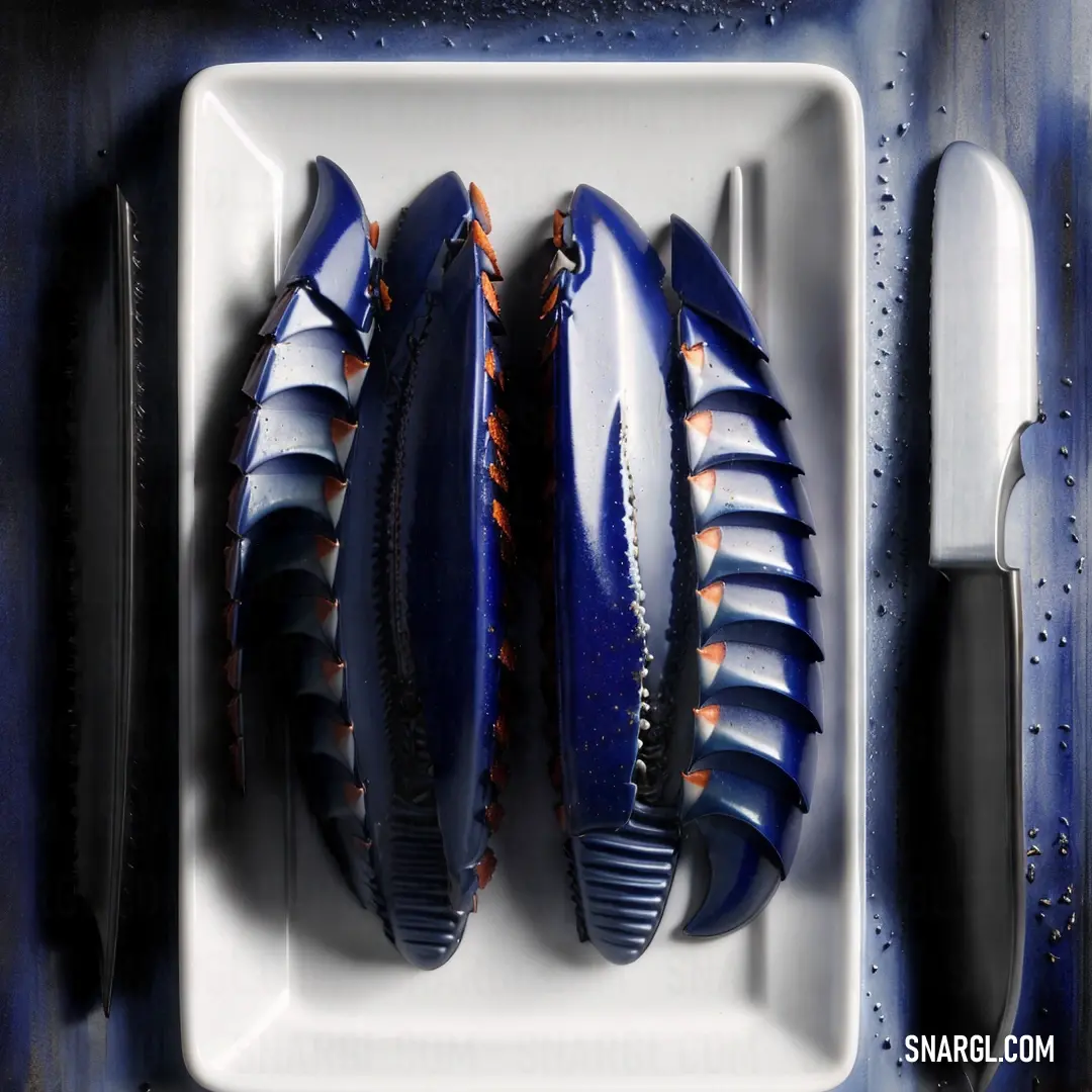 A white plate adorned with a vibrant mix of blue and orange foods, sitting next to a knife, fork, and a knife holder. The deep brown color of the table provides a beautiful contrast, emphasizing the bright, bold colors of the meal.