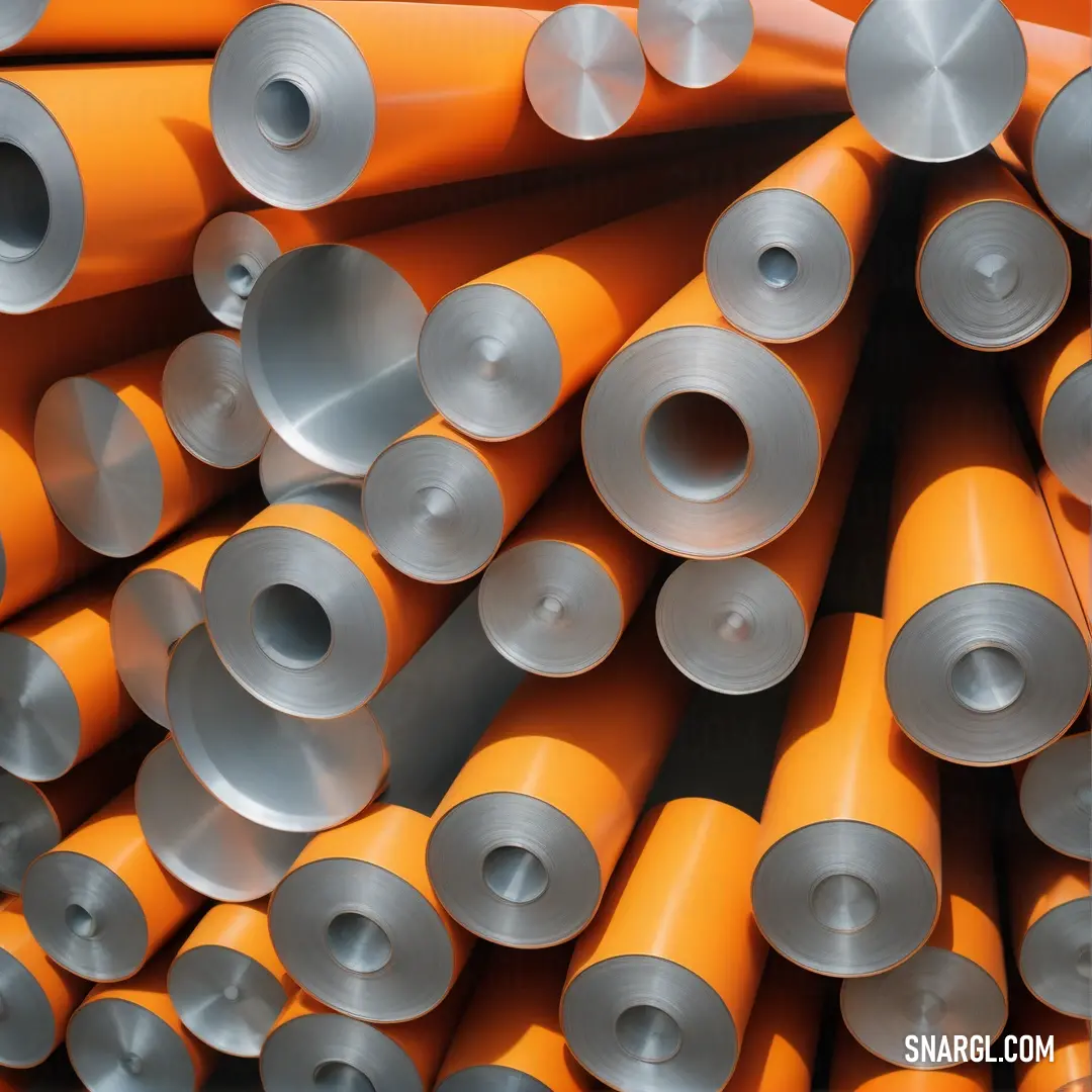 Pile of orange and silver pipes stacked on top of each other in a warehouse or factory area with a black background