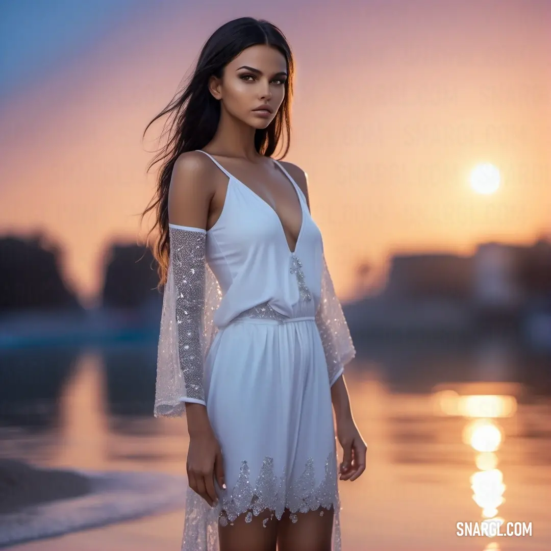 Woman in a white dress standing on a beach at sunset with the sun setting behind her and the water reflecting off of her body